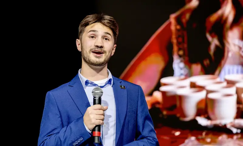 Gavin Robillard speaks while holding a microphone.