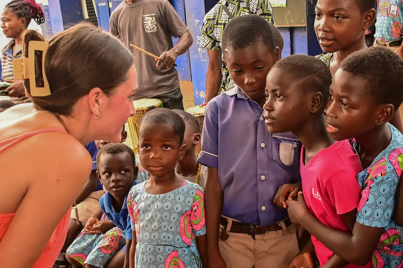 A college student interacts with a group of children at a school in Ghana.