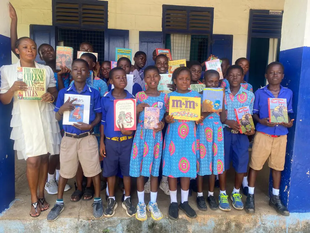 Students and teacher from Ghana hold up donated books