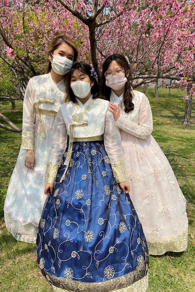 Three women pose for a photo while wearing traditional Korean gowns