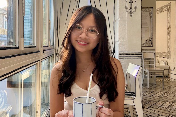 Student Trang Vy Bui smiles for a photo while sitting at a table in a restaurant