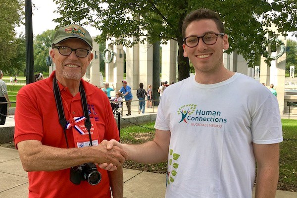 Student Maxwell Aaronson shakes hands with a man while posing for a photo outdoors