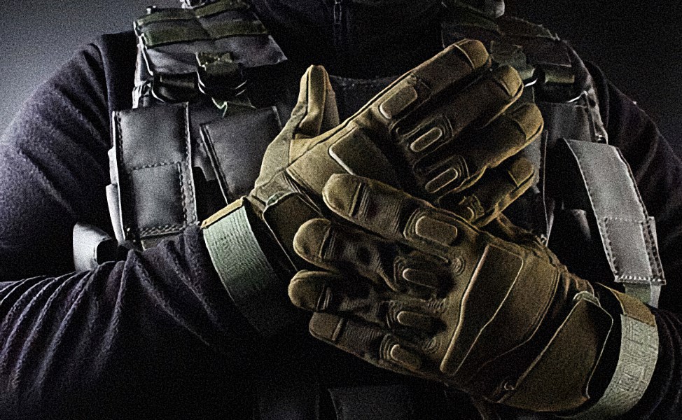 Soldier image cropped closely to their tan gloves on display with a dark background.