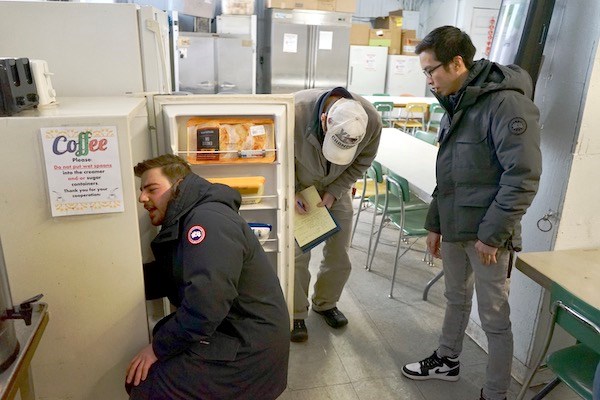 Engineering students look at a refrigerator while doing an energy audit
