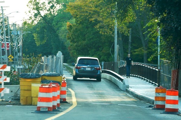 A car and pedestrian cross the new Pawtucket Canal bridge still under construction