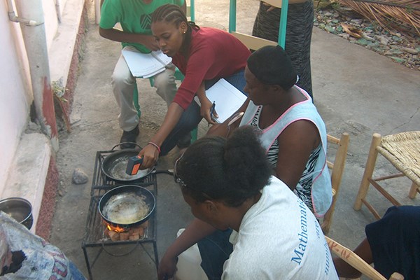 Dayana Alabre checks the temperature of pans used in a cook-off at a demonstration of eco-friendly fuel.
