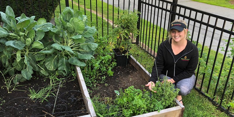 Haylee Dussault shows of some fresh herbs and veggies in a small garden