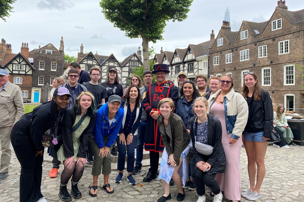 A group of students pose with a man dressed in an old English costume at the Tower of London