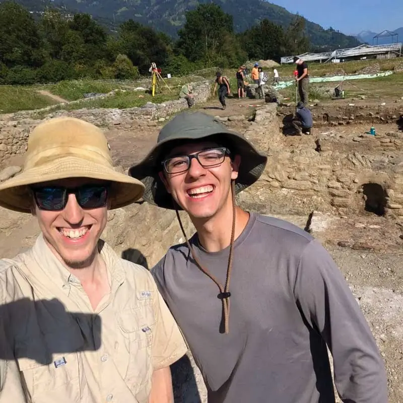 Two UMass Lowell history major students pose at a dig site.