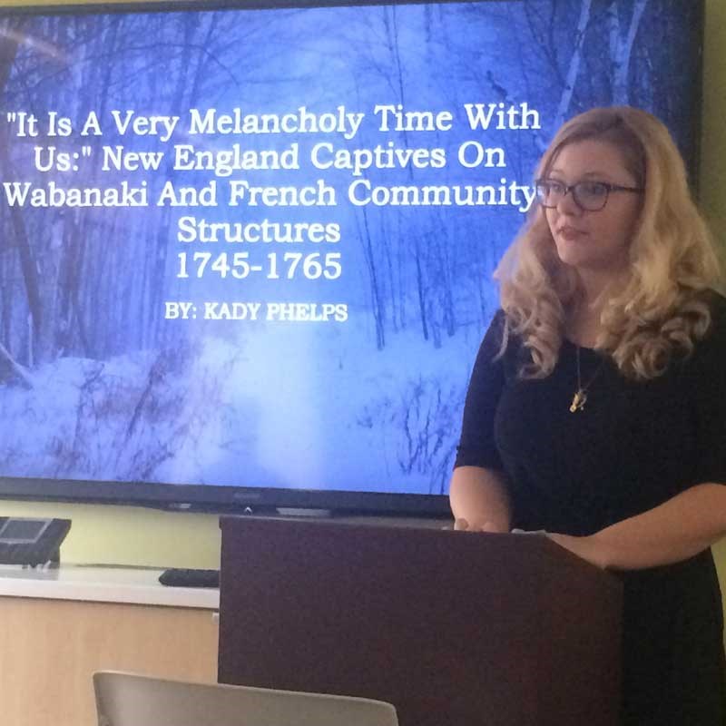 UMass Lowell history student Kady Phelps delivers a lecture at a podium.