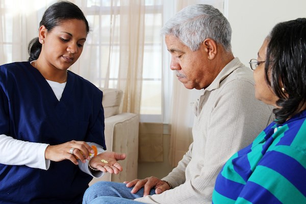 Home care worker helping elderly with medications