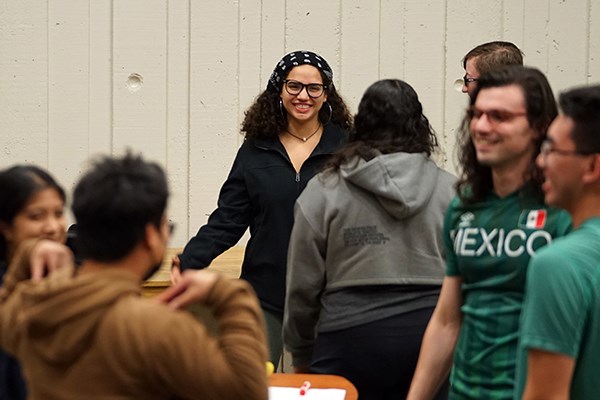 A woman in glasses smiles while standing with a small group of other students