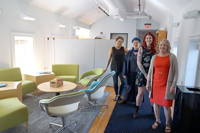 Four people pose for a photo while standing next to furniture in a room