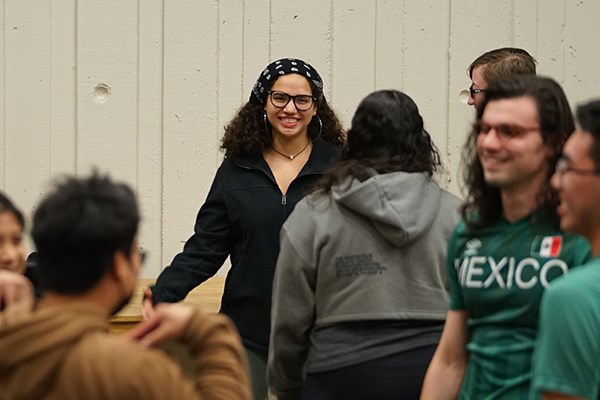 A woman in glasses and a bandana smiles while standing with several other people