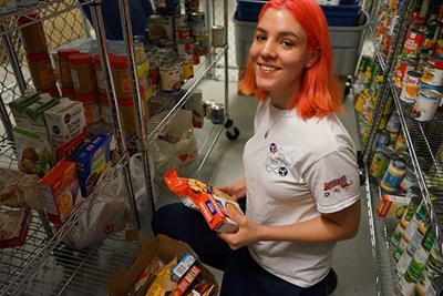 UML first-year honors nursing major Diana Whitcomb sorts food in the storage area for the Navigators Food Pantry on campus