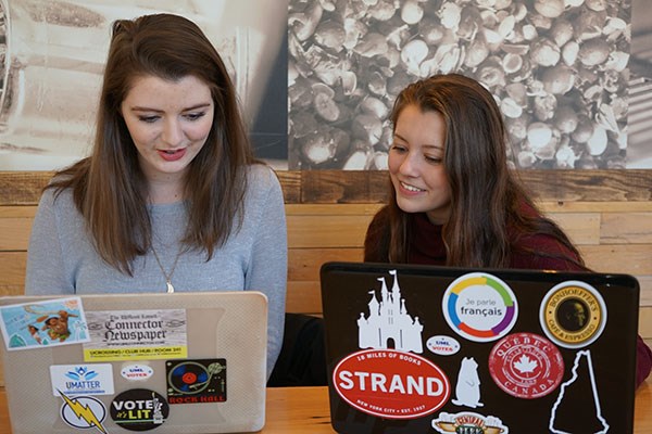 Michaela Goss, left, and Katrina Desrosiers work on Humans of UMass Lowell in their "office" at Starbucks