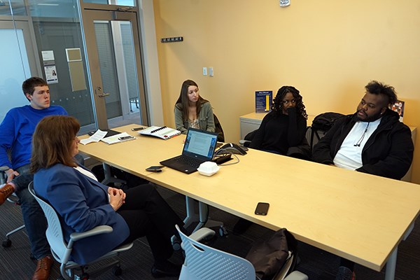 Team members discuss their competition strategy in a meeting at the business school