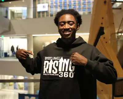 Smiling student wearing a UMass Lowell Rising 360 Office of Multicultural Affairs sweatshirt.