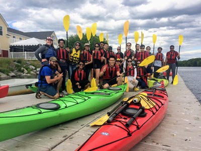 Custom Group Paddle Tour posing for a picture all holding paddles and sitting on and around kayaks.
