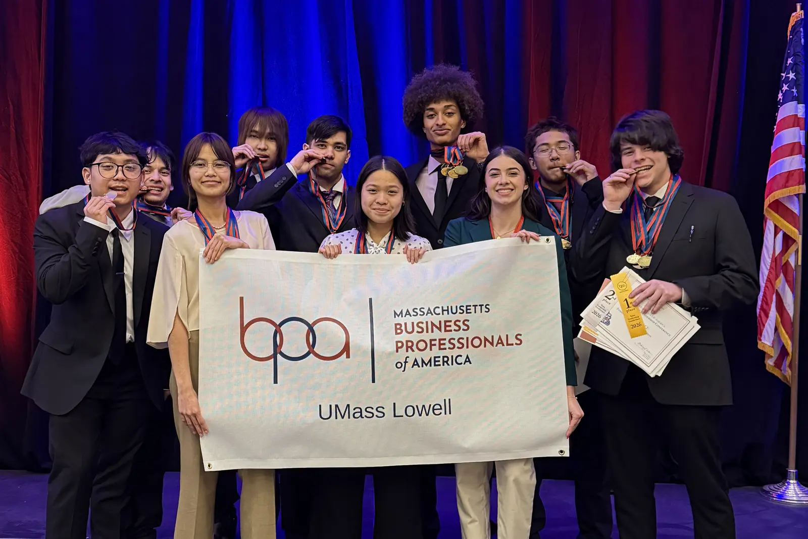 Ten college students pose for a photo while holding a banner and medals.
