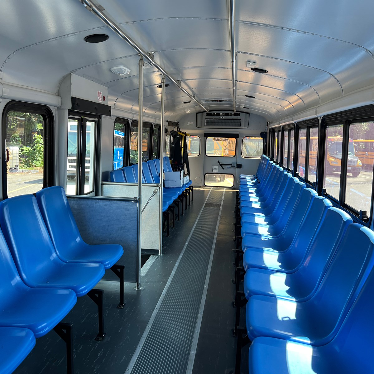 The interior of a UMass Lowell Bus with blue, sideways facing seats.