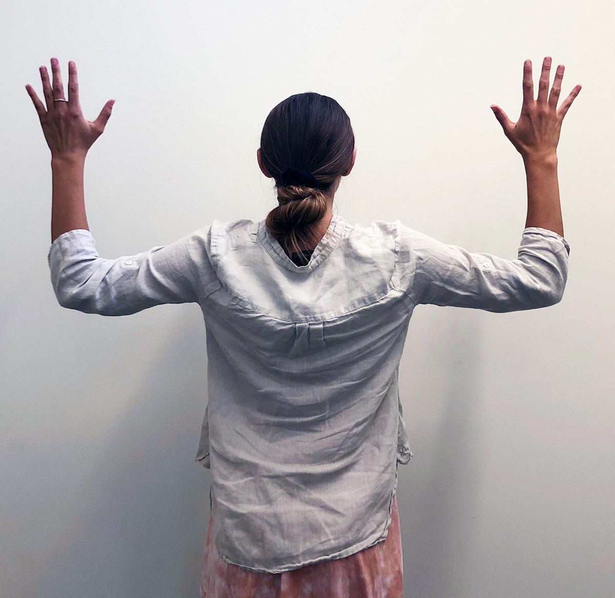 A person raises both arms out to their sides while inhaling. Their elbows are bent to a 90 degree angle and the fingers are pointed towards the ceiling.