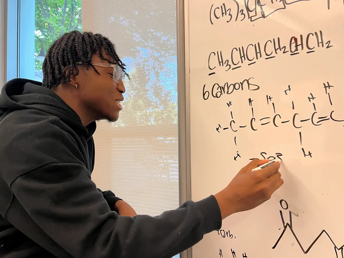 Student writes formulas on a white board