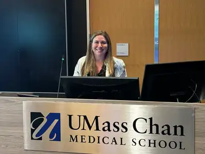 A woman smiles while posing for a photo behind a medical school lecturne.