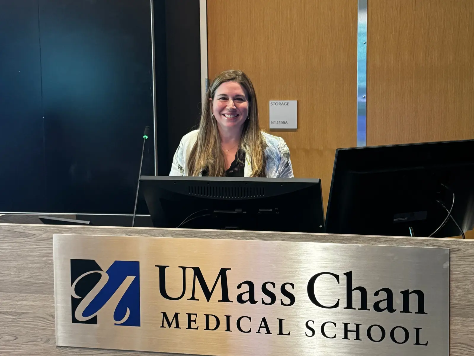 A woman smiles while posing for a photo behind a medical school lecturne.