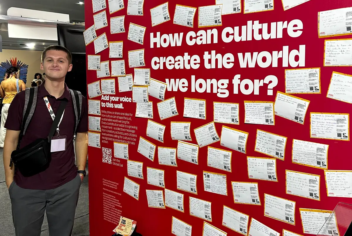 Andrew Fenner stands next to artwork about culture.
