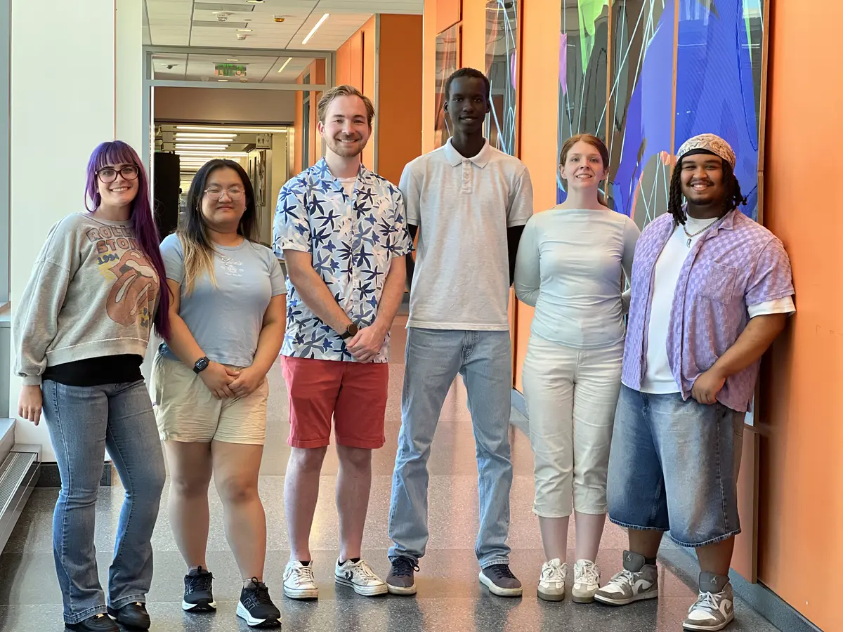 Six people standing and smiling. 