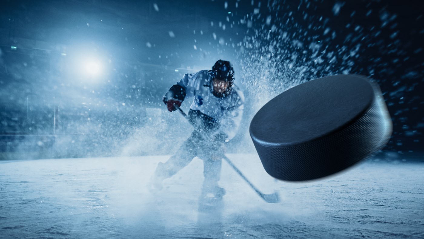Player Shooting the Puck with Hockey Stick. Focus on 3D Flying Puck with Blur Motion Effect. Dramatic Wide Shot, Cinematic Lighting