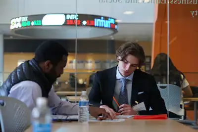 A student looks at a sheet of paper with a mentor.