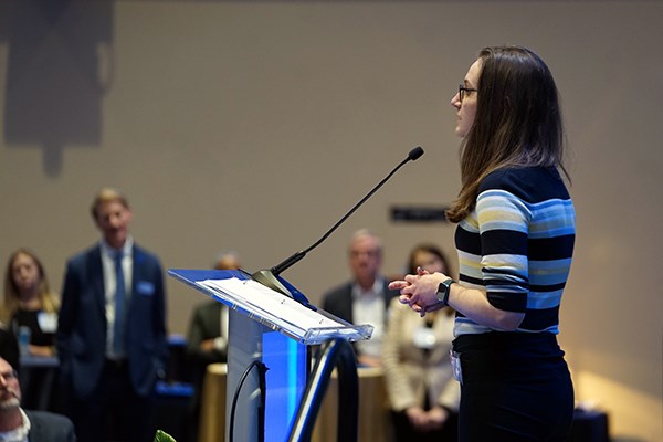 A young woman with glasses makes a speech from a podium