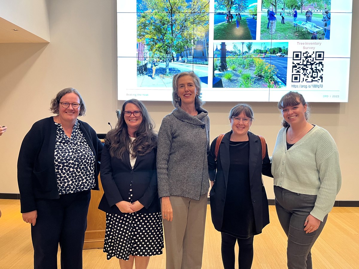 Lucy Hutyra, Katherine Moses, Marie Frank, Jess Wilson and Sophie Mortimer pose for a photo in front of a collage of images and a QR code.