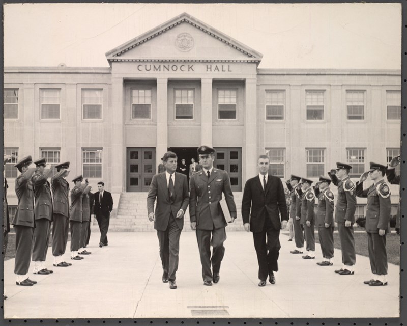A striking image of Massachusetts Sen. John F. Kennedy leaving Cumnock Hall surrounded by saluting officers 