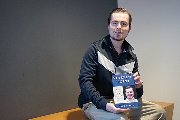 Jack Travis poses with his new book in Pulichino Tong Business Center