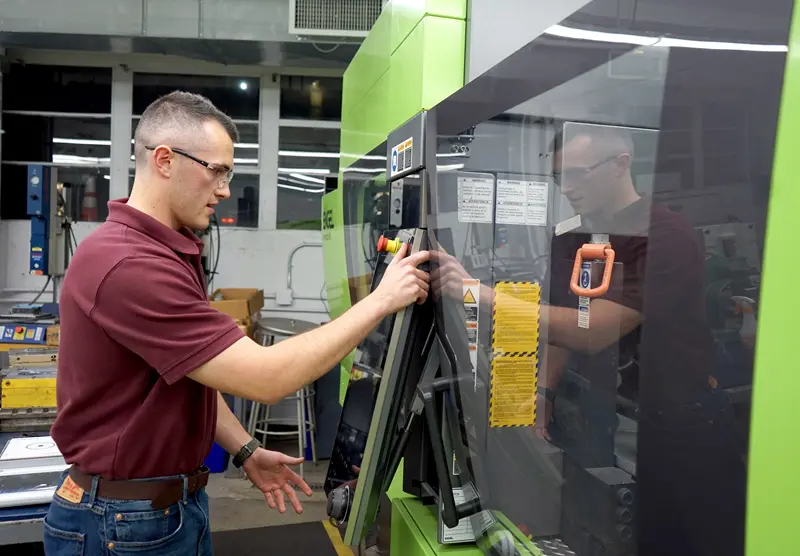 Jack Sullivan works with machinery in a UMass Lowell plastics engineering lab.