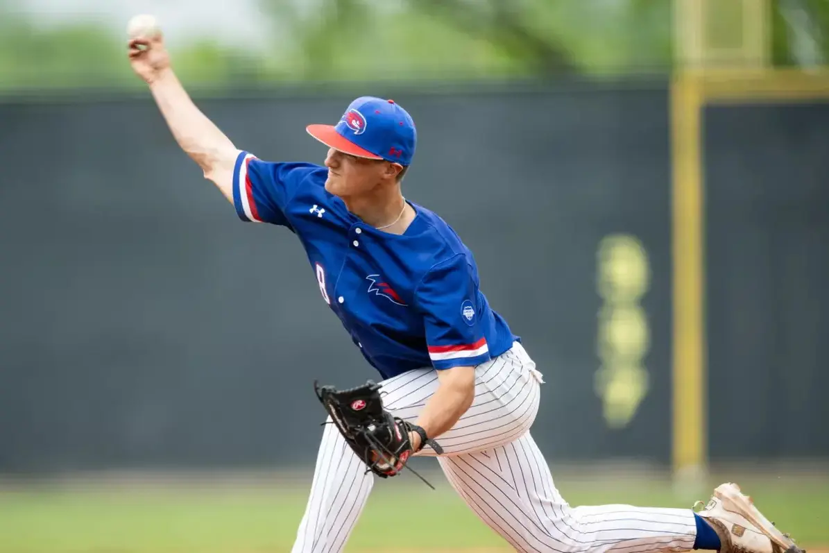 A baseball pitcher in a blue uniform delivers a pitch.