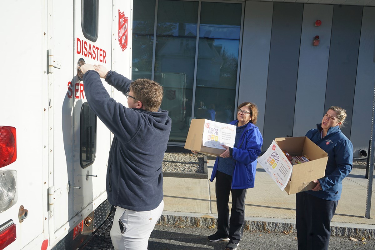 Jayson DeLong opens truck door for two women carrying boxes