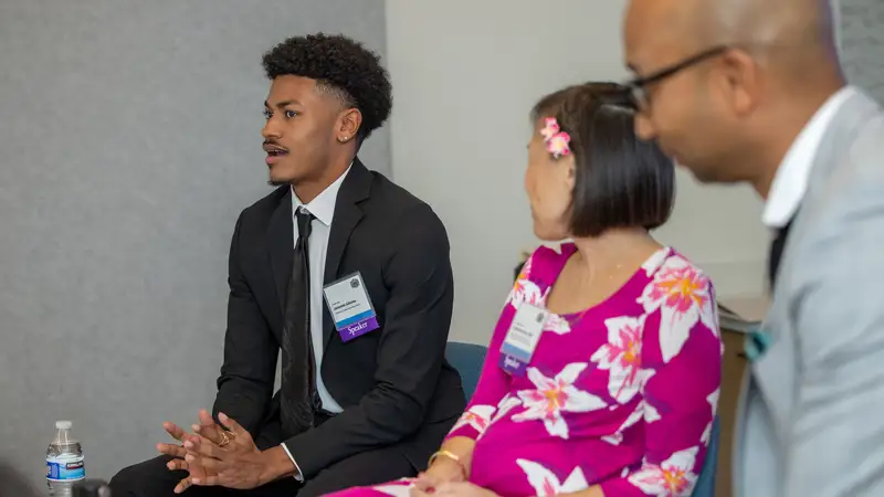 Jeremiah Adames sitting and speaking with two people.