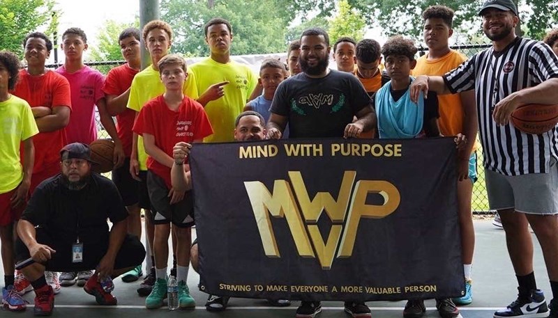 UMass Lowell business major Jeurys Santiago stands with a group holding a banner with the name of his networking and marketing company, Minds With Purpose