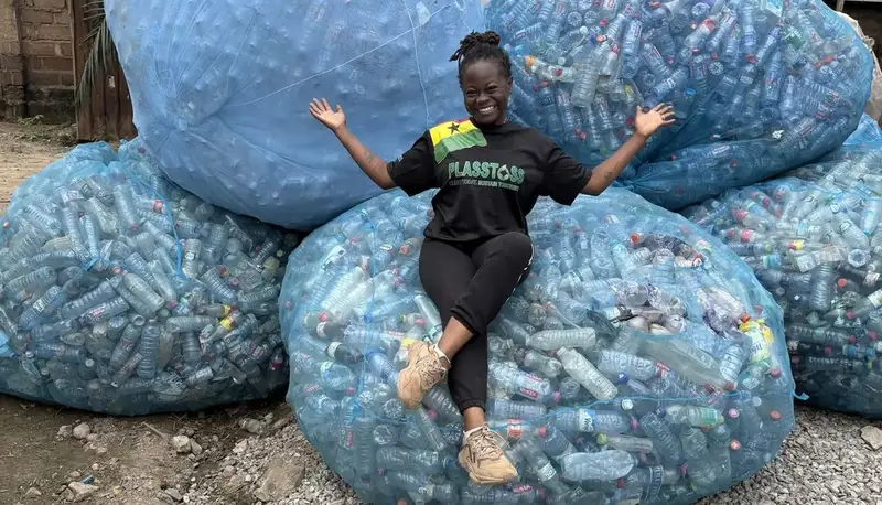 Joanita Amoah sits on bags filled with plastic bottles.