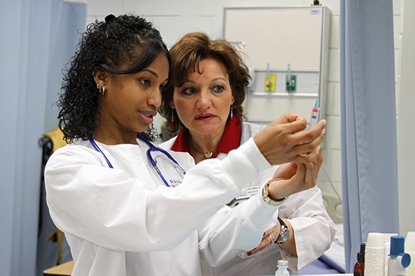 A nursing student works with a faculty member
