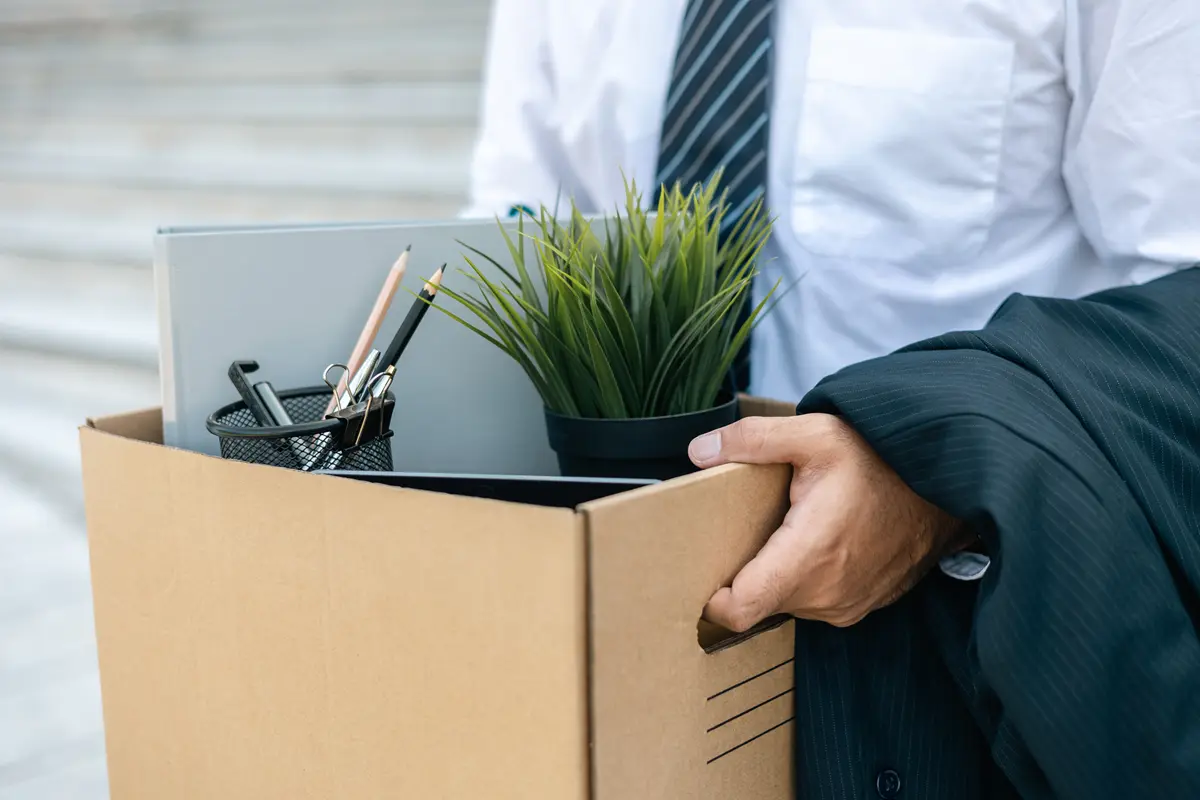 A man takes a box of his personal belongings outside due to unemployment.