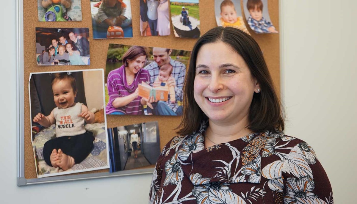 UMass Lowell Disability Services Director Jodi Rachins poses in front of a bulletin board featuring family photos