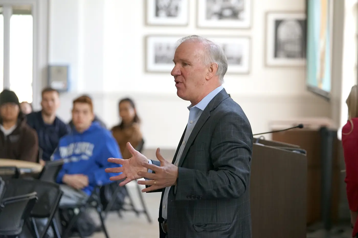 A person in a suit talks to students in a room.