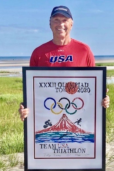 A man in a red USA T-shirt holds a framed poster for the Olympics while standing outside