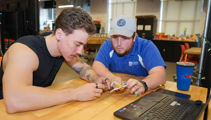 Josh Barosin examines rocket electronic hardware and software with another student.