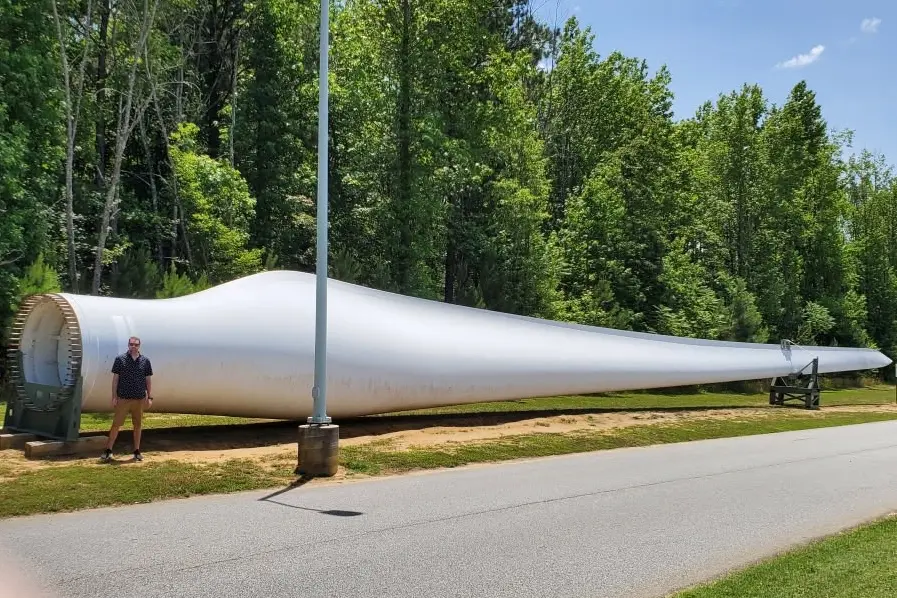 Joshua Morris stands next to a wind turbine blade.